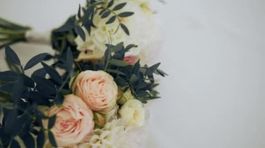 Nedimelere hediye olarak üç buket çiçek beyaz bir masa örtüsünün üzerinde yatıyor. Çiçekçi gülleri, şakayıkları, kasımpatıları ve rusküs dallarını buketlerde birleştirdi.