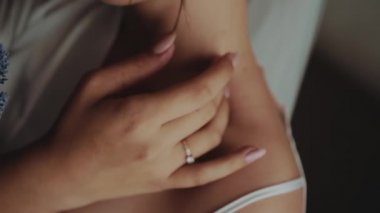 Beyaz cüppeli ve dantelli iç çamaşırlı beyaz bir kız çıplak bir omuz ve nazik, seksi ve romantik bir elle narin boynuna manikür vuruşları yapar.