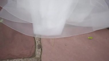 Bir çift yeni evli adam mavi takım elbiseli ve siyah deri ayakkabılı bir adam ve uzun peçeli beyaz elbiseli bir kız hızla fayans yolunda ilerliyorlar.