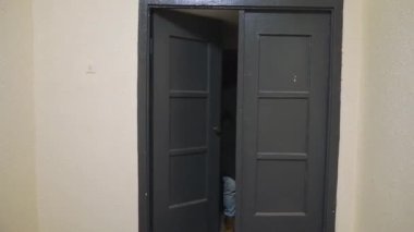 Bıyıklı genç bir adam ahşap kapıdan girer ve yüzünde öfke ve tiksintiyle karanlık korkunç odaya bakar ve çarpık bir yüzle rahatsız olur.