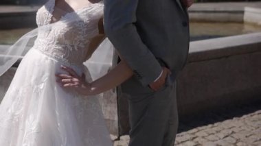 Güneşli bir günde bahçede durup birbirlerine poz veren tuhaf bir çift gelin ve damat.