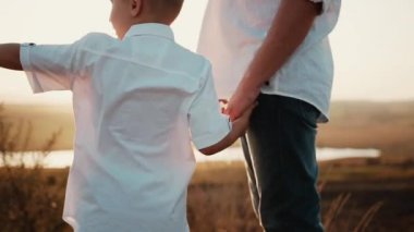 Çocuk ve yetişkin baba eşit giyinmiş gün batımında altın tarlasında el ele tutuşuyorlar. Oğul başka yere bakar ve bir şey gösterir baba. Mutlu aile günü ebeveynleri güzel bir çocukla vakit geçirir. Küçük bir adam yetiştiriyorum