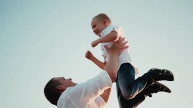 Şanslı baba gün batımında mavi gökyüzünde neşeli bir oğlan çocuğu fırlatıyor. Baba ve küçük çocuk oynuyorlar, gülüyorlar. Çocuğun ebeveyn gülümsemesinin kollarında olmasına sevindim. Baba izinli. Mutlu aile kavramı.