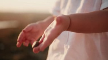 Beyaz bir yaz elbisesi içinde gün batımında beyaz beyaz bir kız çocuğu elinde çakıl taşlarıyla duruyor ve biri fırlatıyor ve diğeri anne babasına veriyor. Doğayla bütünlüğün yakın çekimi