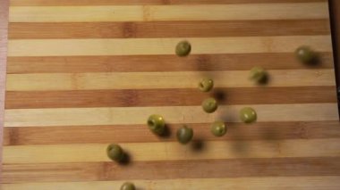 GDO 'suz bir avuç yeşil organik zeytin masaya düşüp farklı yönlere uçuyor. Üst görünüm
