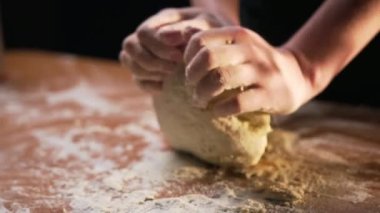 Şef ahşap bir masada lezzetli bir İtalyan pizza tabağı için hamuru un ve yumurtayla yoğurur. Yakın plan. Yavaş