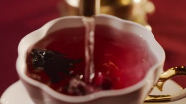 Beyaz seramik fincanda, çay Roselle Hibiscus Sabdariffa 'nın kurumuş perianth çiçeklerinden demlenir. Parlak kırmızı renkli ekşi bir içecek. Çaydanlık ya da semaverden fışkıran suyun yakın çekim akışı