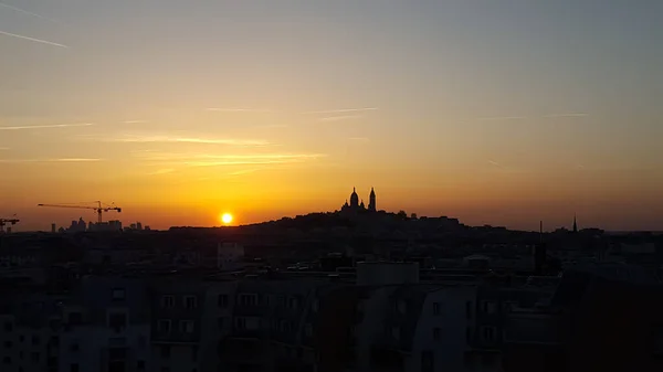 パリの晴れた日にリラックスした夕日 空の色は紫 オレンジで輝きます モンマルトルのサクレ クール教会のシルエットが背景にあります — ストック写真