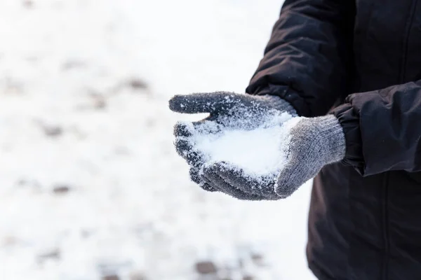 Hands in gray winter gloves. Palm with a glove in the snow. The guy threw snow.