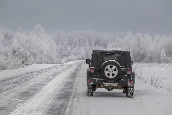 2021年1月17日在列宁格勒地区一条被雪覆盖的道路上的黑色吉普牧羊车 Wrangler 一种由克莱斯勒公司生产的框架Suv 免版税图库图片