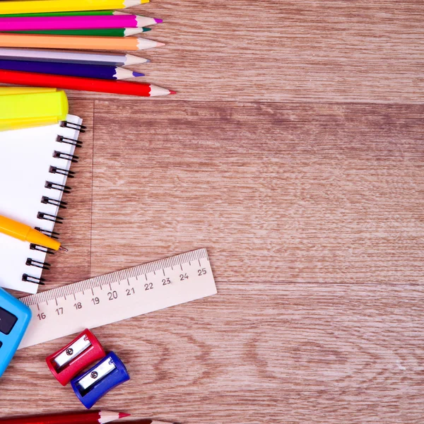 Materiale scolastico e quaderno controllato su fondo legno — Foto Stock