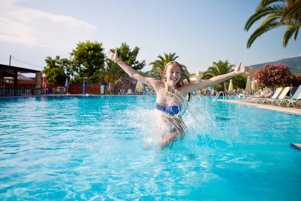 Vrolijke meisje springen in het zwembad op vakantie — Stockfoto