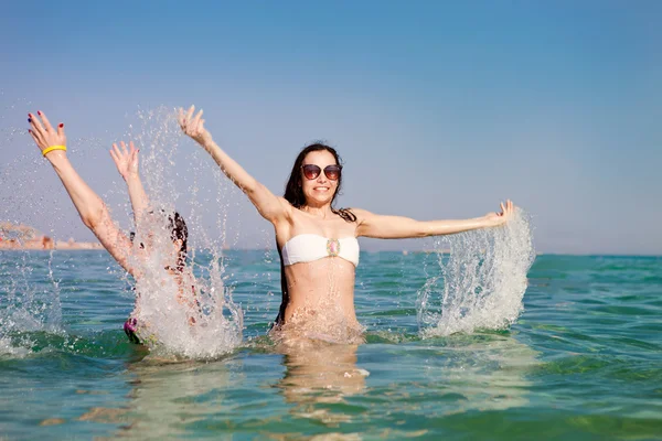 Jeune femme asperge d'eau dans la mer — Photo