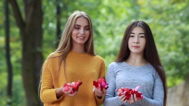 Two happy girlfriends throw rose petals at the top — Stock Video