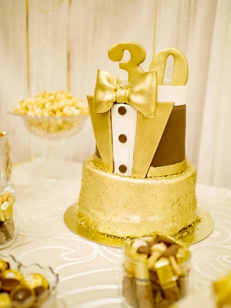 Hermoso pastel de cumpleaños de oro para un hombre en la forma del número treinta sobre un fondo claro —  Fotos de Stock