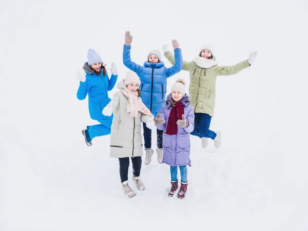 Ragazze gioiose stanno saltando mano nella mano in inverno su una passeggiata. Vestiti invernali alla moda — Foto Stock