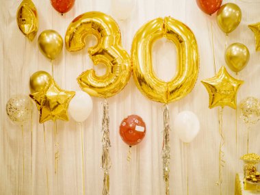 Altın ve beyaz renkli helyum balonlarından oluşan parlak bir kompozisyon ve büyük bir otuz altın çiçek figürü..