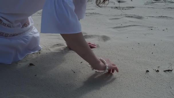 Дівчина малює серце на піску на заході сонця в літній любові концепції — стокове відео