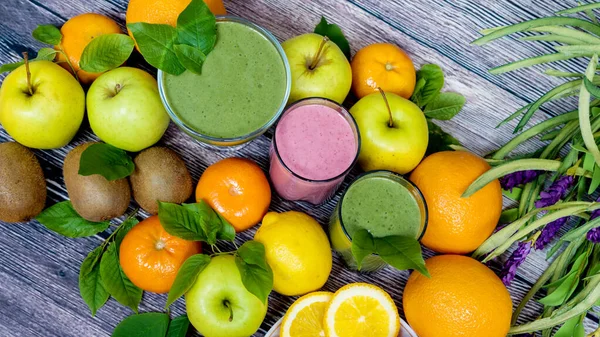 Vers fruit op een houten ondergrond en drie glazen smoothies. Ontgiften. Het juiste eten. Uitzicht van bovenaf Rechtenvrije Stockfoto's