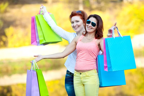 Two girls with bags after shopping in the park — Stock Photo, Image