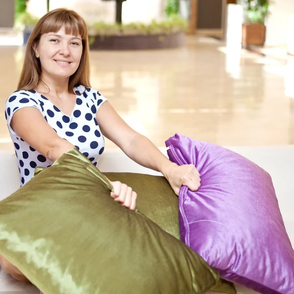 Mujer feliz sentada en casa con cojines de colores — Foto de Stock