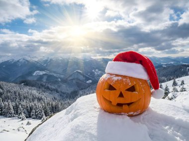 Bu çarpıcı ve alışılmadık görüntü, tatil temalarının büyüleyici bir karışımını sunuyor. Geleneksel ürkünç bir yüze sahip oyulmuş bir balkabağı kırmızı Noel Baba şapkasıyla garip bir şekilde süslenir.