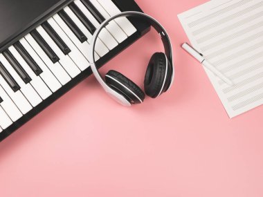 Elektronik piyanonun üst görüntüsü ya da düz kulaklığı, Pembe arka planda boş müzik sayfası kopya alanı..