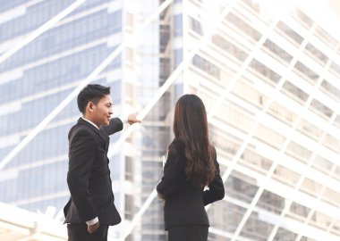 Takım elbiseli genç Asyalı iş adamı ve kadının ofis cephesine bakması, dikkat çekmesi, gayrimenkul tartışması. Ticari gayrimenkul kavramı