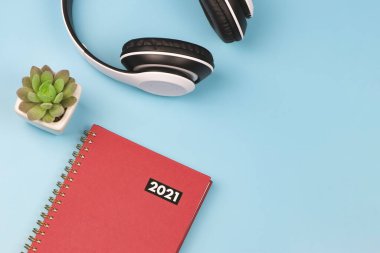 Kırmızı günlük ya da 2021 yılının en iyi görüntüsü sulu saksı ve mavi arka planda kulaklıklar. Yeni yıl 2021 planlama konsepti.