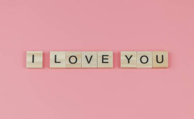 Üst ya da düz tahta harflerle pembe arka planda seni seviyorum. Sevgililer Günü konsepti.