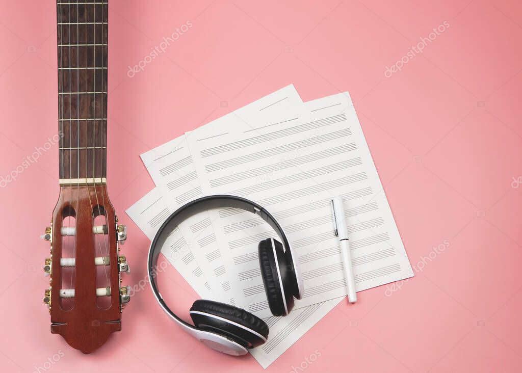 Top view or flat lay of blank music sheet, headphones and acoustic guitar. Musician and leisure concept.