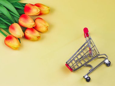 Sarı zemin üzerinde sarı kırmızı laleler olan düz bir alışveriş kartı. Bahar alışveriş konsepti.