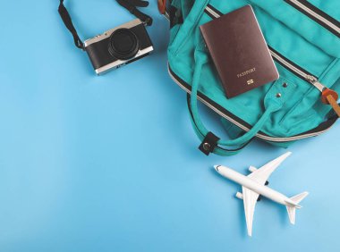 Üst ya da düz pasaport, yeşil sırt çantası, mavi arka planda kamera ve uçak modeli. Seyahat kavramı.