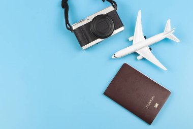 Üst ya da düz pasaport, uçak modeli ve mavi arka plandaki kamera. Mavi arka planda seyahat eden aksesuarlar. Seyahat kavramı.