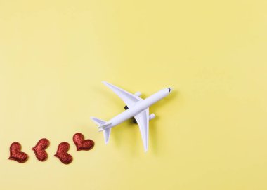 Sarı zemin üzerinde kırmızı kalpler olan uçak modelinin üstü ya da düzlüğü. Balayı gezisi ya da seyahat aşığı konsepti.