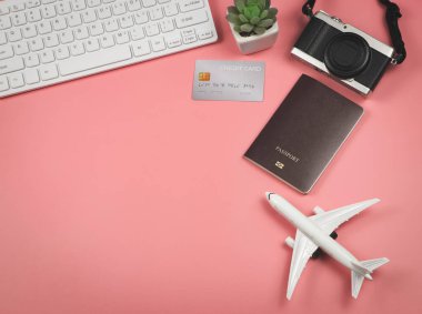 Uçak modeli, bilgisayar klavyesi, kredi kartı, kamera ve kaktüs üzerinde pembe arka plan, iş ve seyahat kavramının üst görünümü veya düzlüğü.