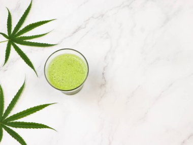 Beyaz mermer zemin üzerinde esrar smoothie suyu ve marihuana yaprakları üst görünüm veya düz yatar.