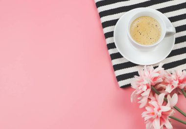 Pembe arka planda pembe çiçekli siyah beyaz çizgili kahve fincanının üst veya düz uzantısı ve boşluğu kopyala.