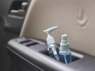 Alkol spreyi şişesi ve alkol dezenfekte edici el jelini arabanın kapı kolluk depolarında kapat. Covid19 önleme ve yeni normal kavram.