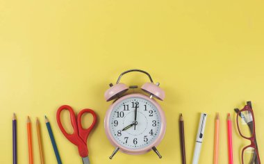 Okul gereçleri, kırtasiye malzemeleri ve saat 8 'de sarı arka planda pembe alarmlı saat ve fotokopi alanı. Okul konseptine dönelim..