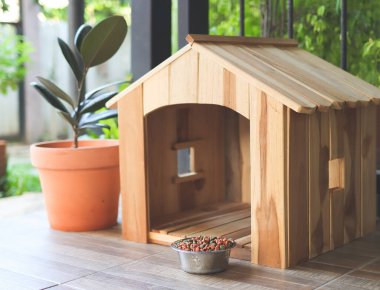 Boş ahşap köpek evi. Balkonda köpek maması kasesi var. Bitki örtüsüyle süslenmiş..