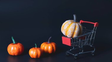Süpermarket arabası ya da siyah arka planda tramvayı olan balkabaklarının ön görüntüsü. Sonbahar Cadılar Bayramı ve Şükran Günü konsepti.