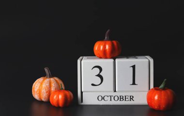 Tahta takvimin ön görüntüsü 31 Ekim Siyah arkaplanda balkabakları. 