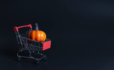 Süpermarket arabasında balkabağı manzarası ya da siyah arka planda tramvay. Sonbahar Cadılar Bayramı ve Şükran Günü konsepti.