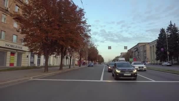 ZAPOROZHYE, UKRAINE - 15 EYLÜL 2020: Akşamleyin trafik ışıklarında caddeden karşıya geçerken, kamera arka plandaki arabalar ve binalar boyunca sorunsuzca hareket eder — Stok video