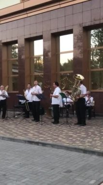 Erkekler beyaz gömlekli müzisyenler restoran orkestrası yakınında müzik çalarlar. Caz festivali yaparlar.