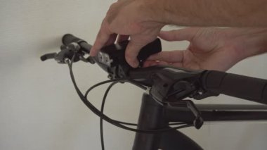 Bir adam motorun gidonuna bir lamba, bir el feneri yerleştirir ve bu aydınlatma cihazının parlaklığını ve çalışma kiplerini bisikletçiler için kontrol eder..