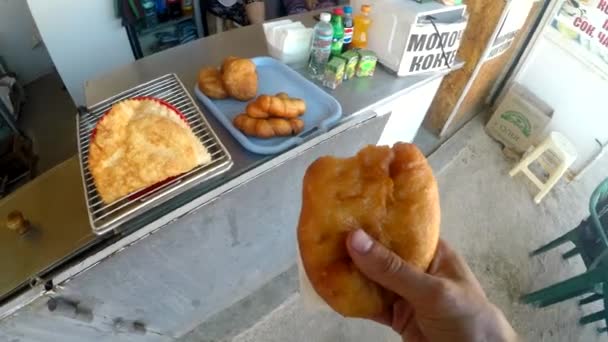 一个男人在街上的食品店里买了一个大馅饼，然后咬了它. — 图库视频影像