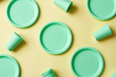 Sarı arka planda plastik tabaklar
