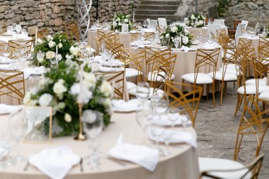 Düğün süslemeleri. Tabaklar beyaz ve altın çerçeveli. Altın çatal bıçak takımı.